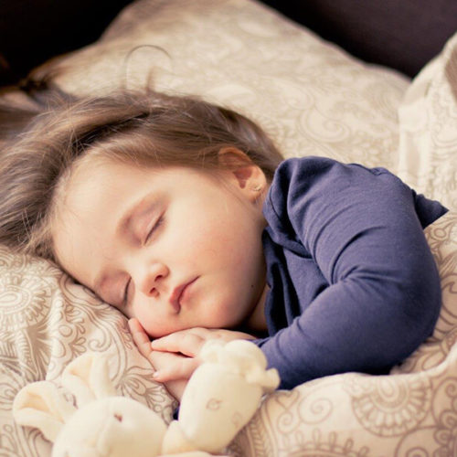 young child in bed with teddy bear