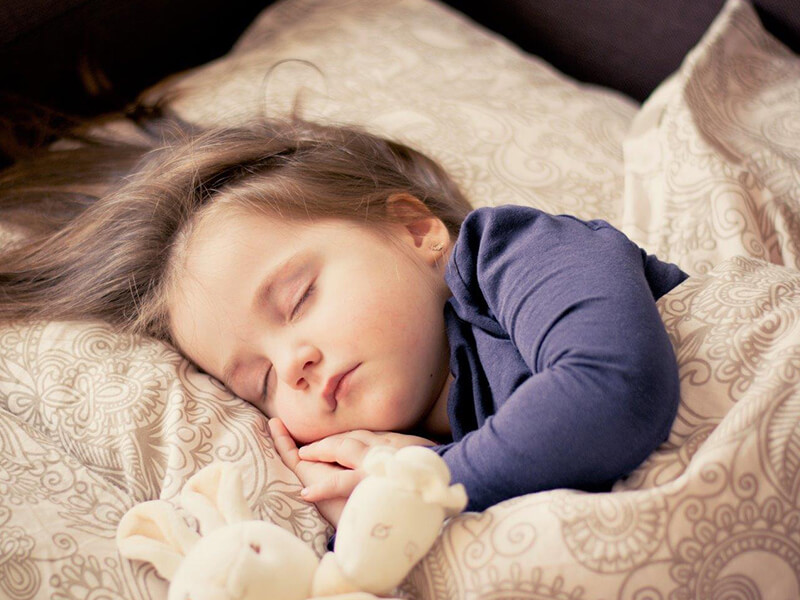 young child in bed with teddy bear